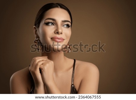 Beauty Model Portrait with plump Lip Makeup looking sideways. Beautiful smiling Woman with smooth Face Skin Make up and Golden Earrings over brown. Dermal Filler Foto stock © 