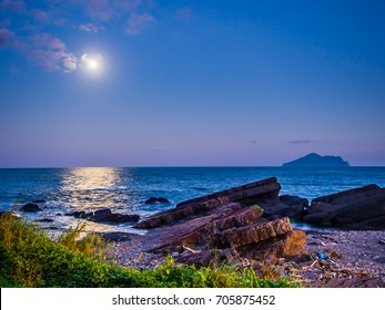 The beauty moment of moon nature and sea. The great supermoon is shining above the Pacific ocean. The moonlight is so strong, the light reflect to the sea in long and wide way toward the rocky shore.