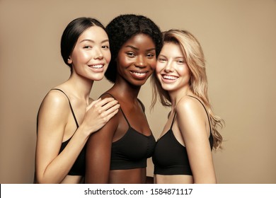 Beauty. Multi Ethnic Group of Womans with diffrent types of skin together and looking on camera. Diverse ethnicity women - Caucasian, African and Asian posing and smiling against beige background. - Shutterstock ID 1584871117