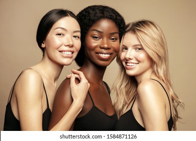 Beauty. Multi Ethnic Group of Womans with diffrent types of skin together and looking on camera. Diverse ethnicity women - Caucasian, African and Asian posing and smiling against beige background.