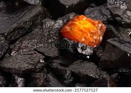 The beauty of natural raw amber. A piece of yellow-red transparent natural amber on a piece of stone wood.