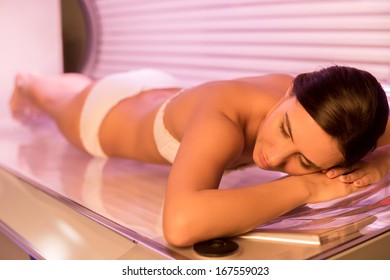 Beauty On Tanning Bed. Top View Of Attractive Young Woman Tanning In Solarium