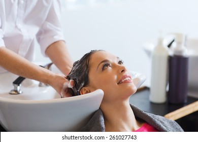 beauty and people concept - happy young woman with hairdresser washing head at hair salon - Powered by Shutterstock