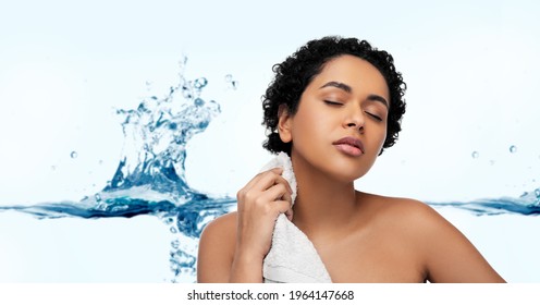 beauty and people concept - portrait of young african american woman with bath towel over white background with bubbles in blue water splash
