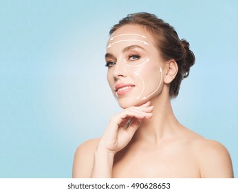 beauty, people, plastic surgery, anti-age and health concept - beautiful young woman touching her face over blue background