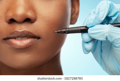 beauty, plastic surgery and people concept - close up of face of beautiful young african american woman and hand in glove with marker over blue background