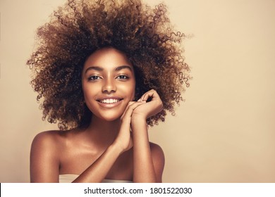 Beauty portrait of african american black woman with clean healthy skin on beige background. Cosmetic and beauty concept. Smiling beautiful afro girl.Curly  afro hair
