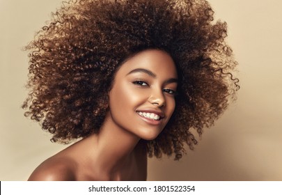 Beauty portrait of african american black woman with clean healthy skin on beige background.  Smiling beautiful afro girl.Curly  hair

