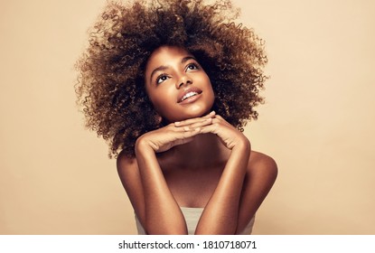 Beauty portrait of african american black  woman with clean healthy skin on beige background. Smiling dreamy beautiful afro girl.Curly  hair