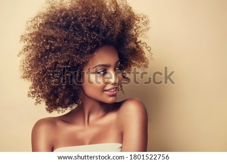 Beauty portrait of african american black woman with clean healthy skin on beige background. Skin care and cosmetic. Smiling beautiful afro girl.Curly  hair
