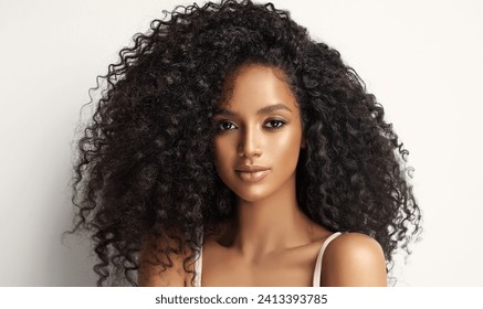 Beauty portrait of african american girl with clean healthy skin on beige background. Smiling dreamy beautiful black woman.Curly  hair in afro style  - Powered by Shutterstock