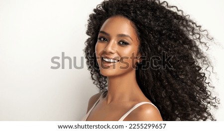 Beauty portrait of african american girl with clean healthy skin on beige background. Smiling dreamy beautiful black woman.Curly  hair in afro style 