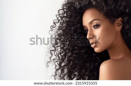 Beauty portrait of african american girl with clean healthy skin on beige background. Smiling dreamy beautiful black woman.Curly  hair in afro style 