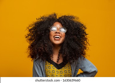 Beauty portrait of african american with glasses and afro hairstyle on a yellow background. Brazilian young woman.