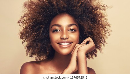 Beauty portrait of african american woman with clean healthy skin on beige background. Smiling beautiful afro girl.Curly black hair
