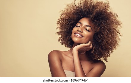 Beauty Portrait Of African American Woman With Clean Healthy Skin On Beige Background. Smiling Beautiful Afro Girl.Curly Black Hair