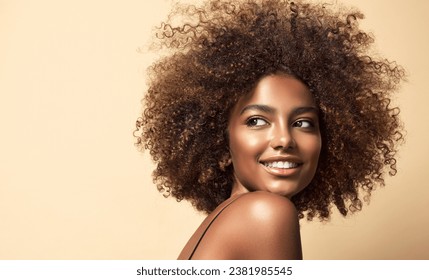 Beauty portrait of african american woman with clean healthy skin on beige background. Smiling dreamy beautiful afro haitstyle  girl.Curly black hair