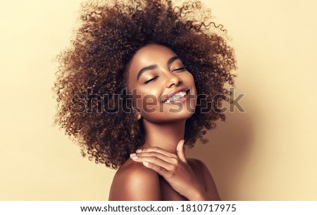Photo of Beauty portrait of african american woman with clean healthy skin on beige background. Smiling dreamy beautiful afro girl.Curly black hair