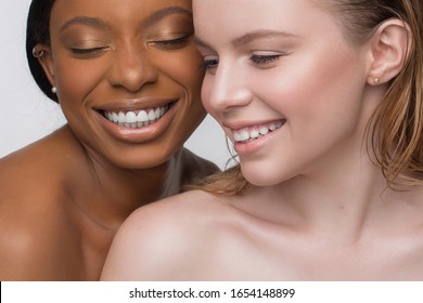 Beauty portrait of africans and europeans girls with bare shoulders and fashionable make  on a white background. Two beautiful girls of different races dark skinned and white skinned with nutural make