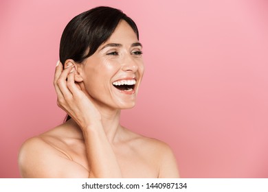 Beauty portrait of an attractive smiling young topless woman standing isolated over pink background, looking away, posing - Shutterstock ID 1440987134