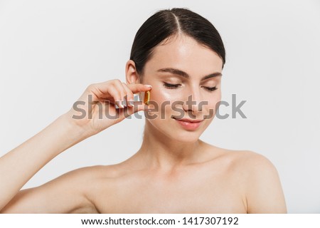 Beauty portrait of an attractive young topless woman isolated over white background, taking beauty pills