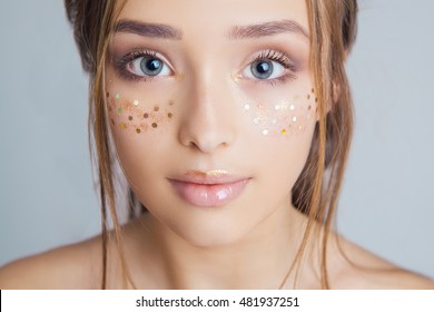Beauty Portrait. Beautiful Spa Woman . Perfect Fresh Skin. Big blue eyes with eyelashes in golden glitter. Golden glitter freckles