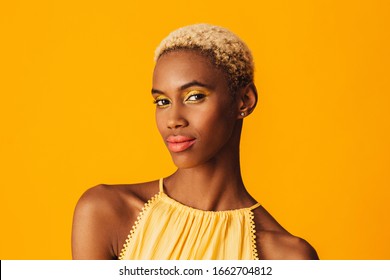 Beauty Portrait Of A Beautiful Young Woman With Bright Yellow Eye Shadow Make Up And Bold Pink Orange Lips Looking At Camera