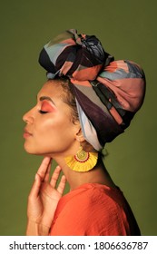 Beauty Portrait Of Black African American Woman In  Orange Clothing And Ethnic Head Wrap  I Poing In Studio. Bright Make Up. 