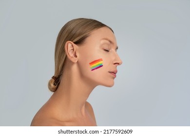 Beauty Portrait Of Blonde Woman With Colorful Painted Rainbow On Her Face. LGBT Flag. The Concept Of Equality And Support Of Diversities To People.
