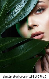 Beauty Portrait Of Brunette Girl In Palm Leaves. Beautiful Young Woman With Make-up. Natural Cosmetics Concept