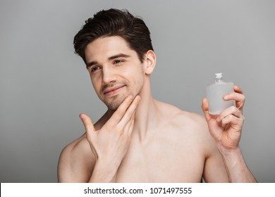 Beauty Portrait Of Half Naked Handsome Young Man Using Aftershave Lotion Isolated Over Gray Background