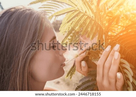 Beauty portrait of happy woman closeup. Young girl smelling Chinese acacia pink blossoming flowers. Portrait of young woman in blooming spring, summer garden. Romantic vibe. Female and nature