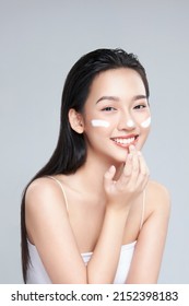 Beauty portrait image of pretty asian woman smiling and applying face cream isolated over light grey background - Shutterstock ID 2152398183