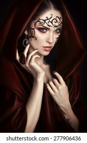 Beauty portrait with lace face-art in red cloak with hood