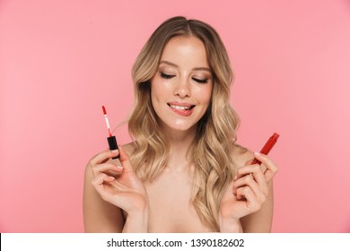 Beauty portrait of a lovely young woman with long blonde hair standing isolated over pink background, showing lipgloss