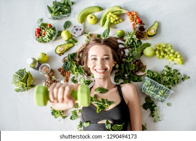 Beauty portrait of a sports woman surrounded by various healthy food lying on the floor. Healthy eating and sports lifestyle concept