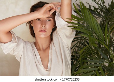 Schönheit. Porträt von Frauen gegen tropische Vegetation. Schönes Modell, das sich in der Nähe von Palmblättern befindet und Kamera ansieht. Bietet Brunette mit natürlicher Schminke, strahlender und glühender Gesichtshaut.