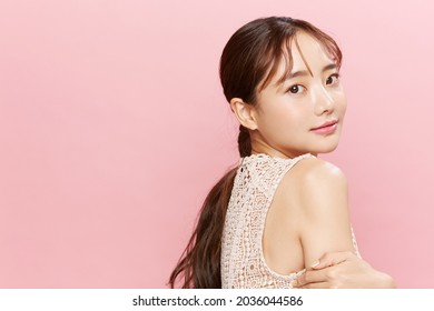 Beauty portrait of young Asian woman in dress on pink background.