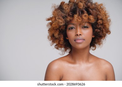 Beauty portrait of young attractive afro woman with perfect skin and delicate glamour makeup with yellow eyeliner. Girl with afro hairstyle looking at camera. Studio shot. A lot of copy space.