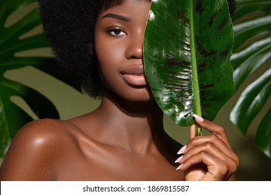 Beauty Portrait Of Young Beautiful African American Woman With Posing With Banana Leaf Curly Hair Against Green Exotixc Plants  Background. Natural Skin Care Concept