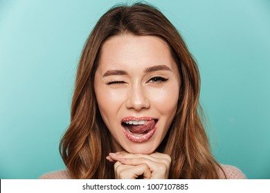Beauty portrait of a young brown haired woman with sparkling makeup winking isolated over blue background