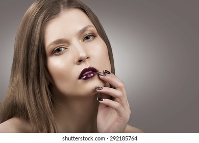 Beauty portrait of a young caucasian girl with long straight fair hair, gray eyes in bright colors, bright lips and clear skin. Posing looking straight into the camera, touching her face.