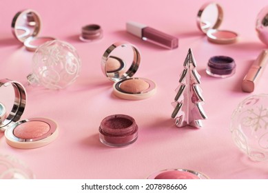 Beauty Products, Christmas Balls And Decorative Christmas Tree On Pink Background. Blushes, Eyeshadow And Lip Gloss. Christmas Party Makeup Concept