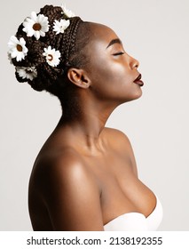 Beauty Profile of African American Woman with White Chamomile Flowers in Black Hair Braids. Fashion Portrait of Dark Skin Model over White. Wedding Make up and Bride Cornrows Hairstyle
