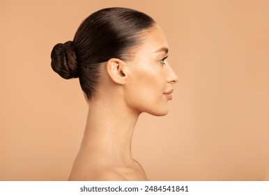 Beauty profile shot of European lady with healthy glowing skin natural makeup, posing isolated on beige background, side view