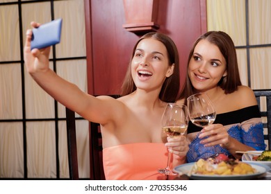 Beauty queens. Two cheerful smiling young women doing selfie with a smartphone in Asian restaurant - Powered by Shutterstock