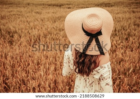 Beauty romantic girl outdoors. Happy young woman in sun hat in summer wheat field at sunset. Copy space, sunset, flare light, summer season. Boho chic style