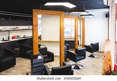 Beauty salon barbershop interior. Large wood-framed mirrors and comfortable black leather armchairs in a modern, cozy and bright space.