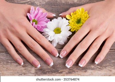 Beauty saloon. Nail salon. Beautiful french manicure with flowers on the old wooden background.