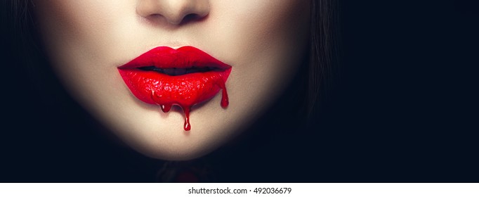 美性感吸血鬼红色的嘴唇滴血近距离。 隔离在黑色背景。